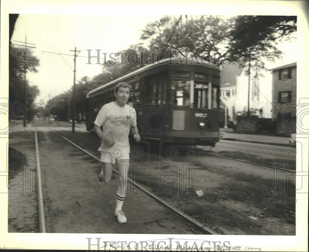 1988 Press Photo Evan Meadow jogs next to a tram- Historic Images