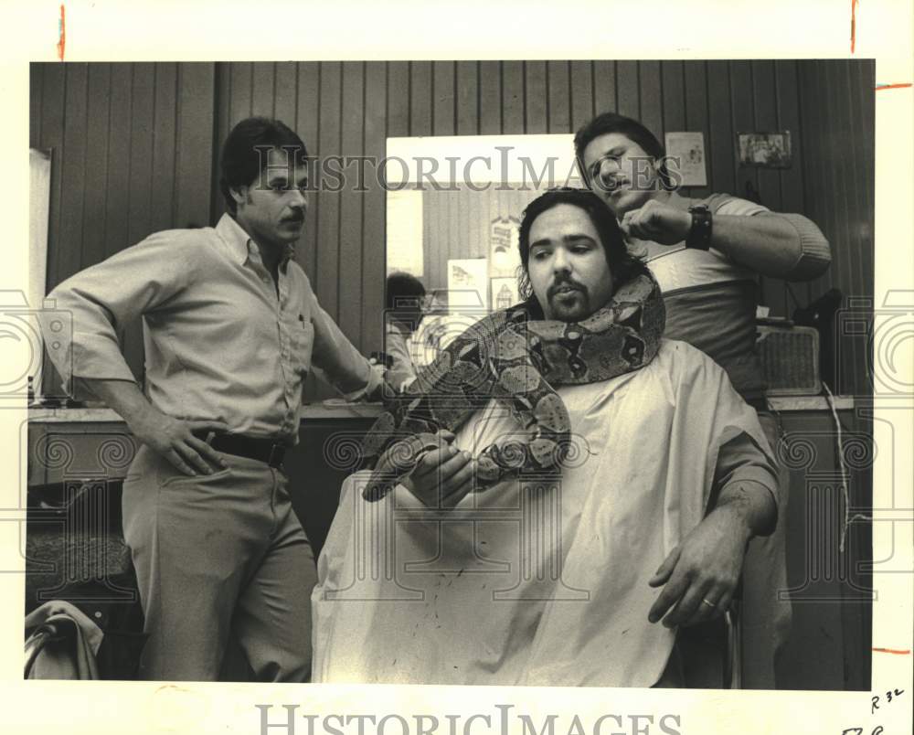 1983 Press Photo Mike Brockhoft hold a snake while getting his hair cut- Historic Images