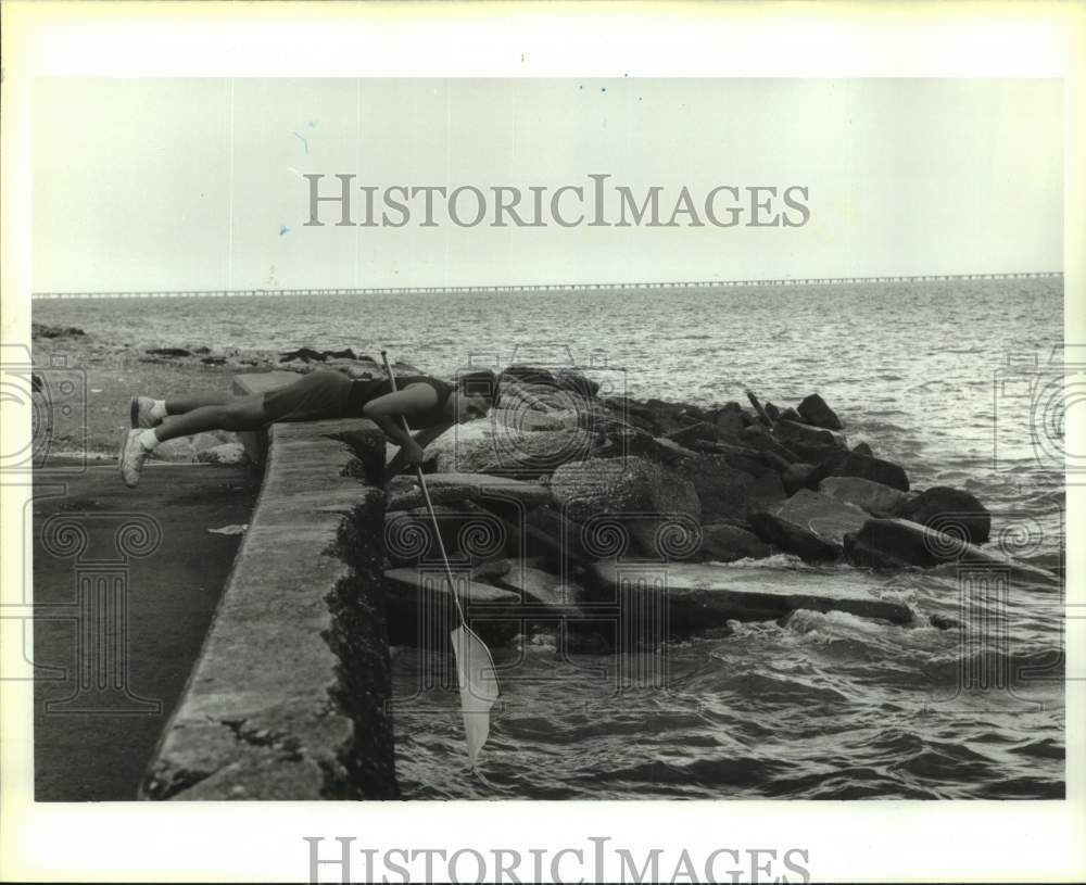 Press Photo Toby Moore leans over sea wall finding a bait- Historic Images