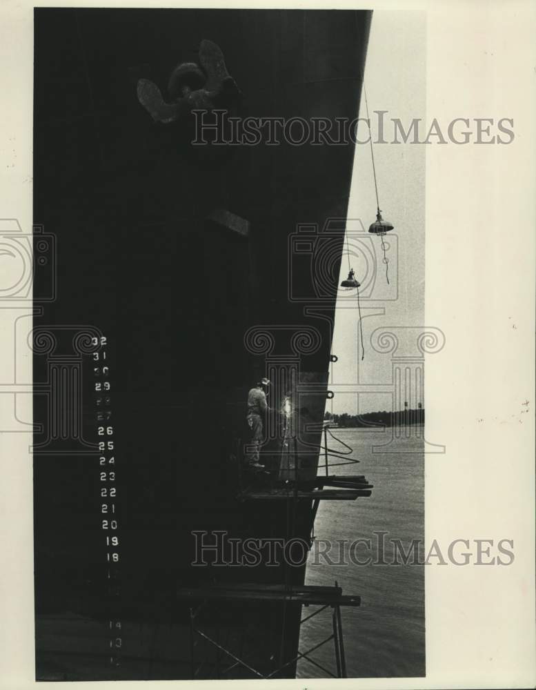 1983 Press Photo Freighter Looms Over Welder, Nashville Ave. Wharf, New Orleans