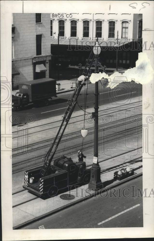 1949 Press Photo Cleaning crews on extended ladder to clean cast iron post