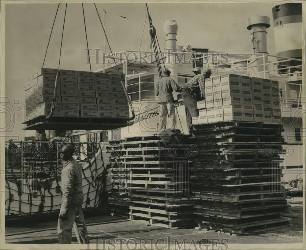 1963 Press Photo Men Work With Crane To Load Cases Onto Ship - nob99074