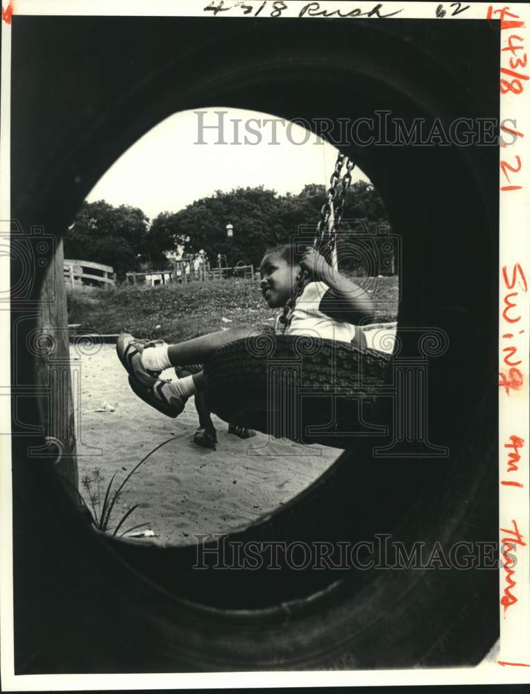 Load image into Gallery viewer, 1980 Press Photo Trishawn Louviere enjoying the tire swings in Palmer Park
