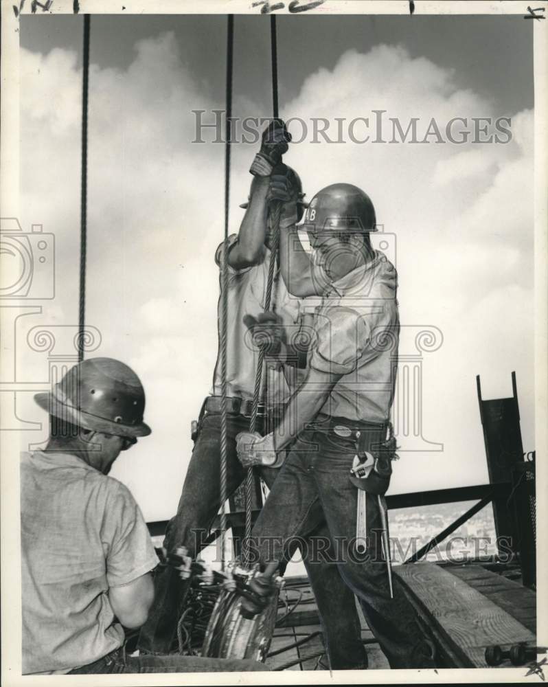 1965 Press Photo &quot;Boomers&quot; tightening the guy wires for the big derrick- Historic Images