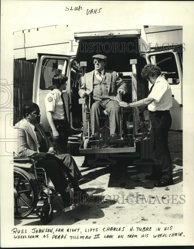 Load image into Gallery viewer, 1985 Press Photo Russ Johnson lifts Charles Tubre in his wheelchair into a van.
