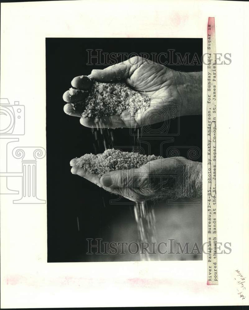 Load image into Gallery viewer, 1985 Press Photo Sugar is poured through hands at the St. James Sugar Co-Op
