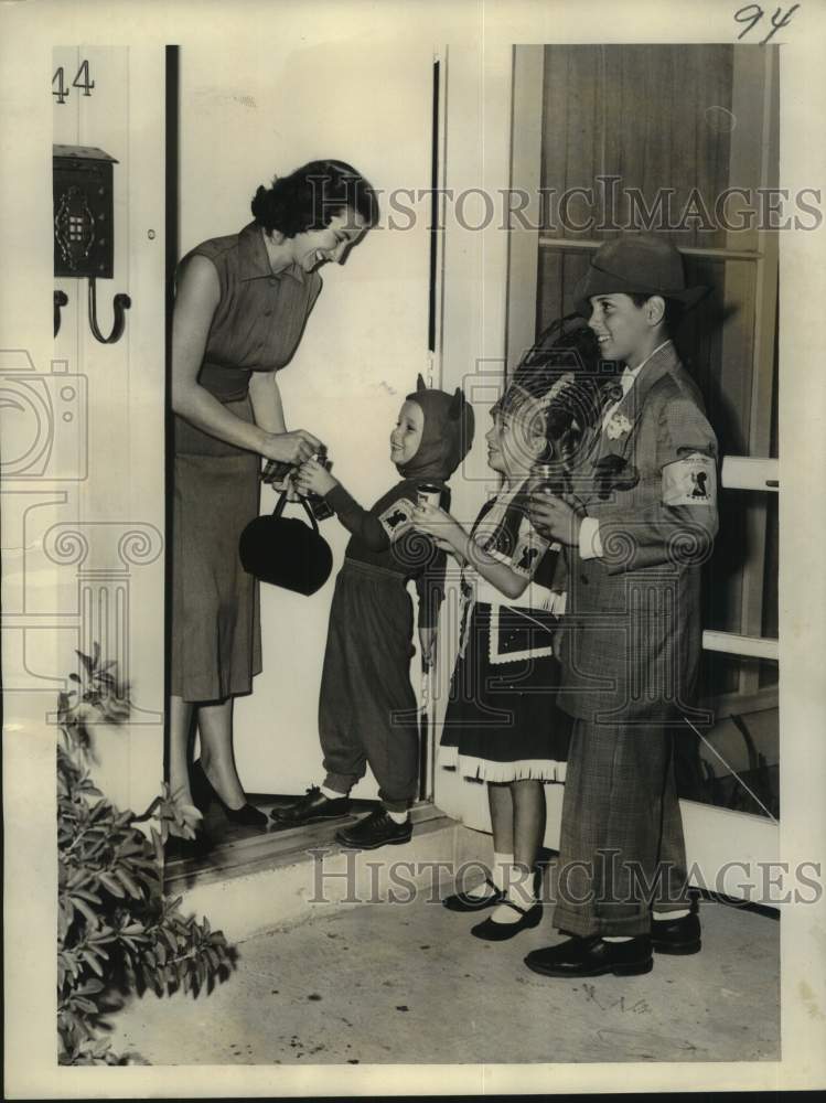 1954 Press Photo Mrs. Robert Wolf hands out treats to "trick-or-treaters."