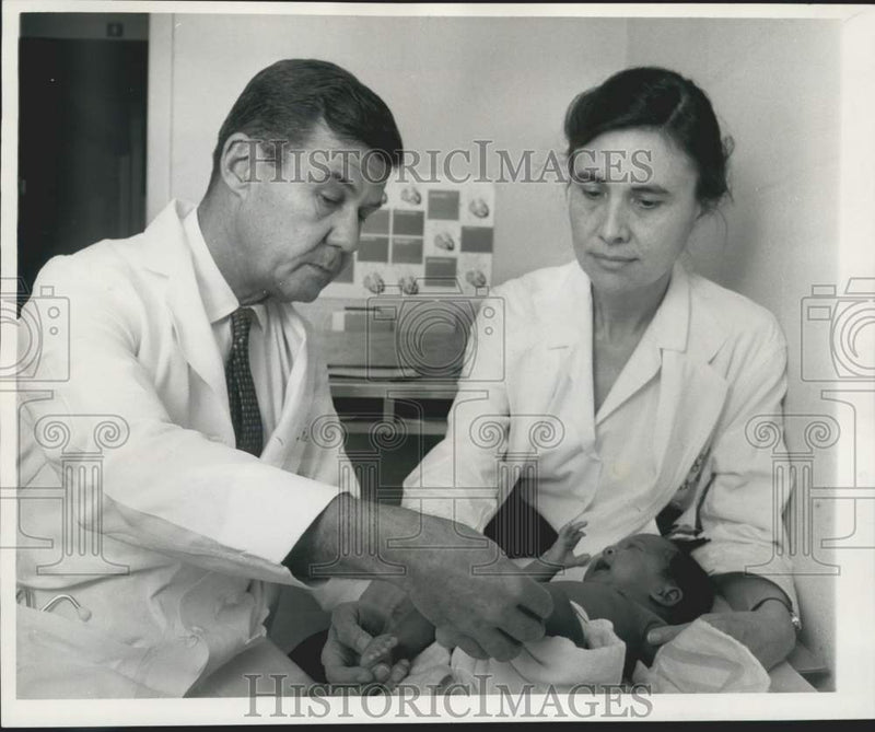 Load image into Gallery viewer, 1966 Press Photo Dr. Norman Woody and wife, Dr. Hannah Woody, examine a baby
