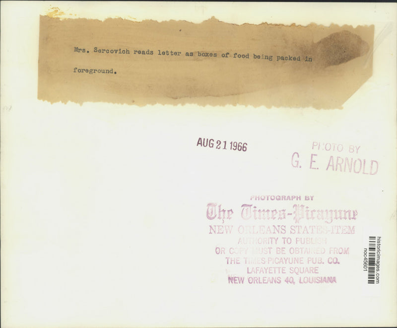 Load image into Gallery viewer, 1966 Press Photo Mrs. Sercovich reads a letter as boxes of food are being packed
