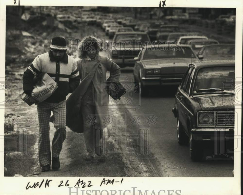 Load image into Gallery viewer, 1985 Press Photo Couple walk busy road during wet cold weather - noc52809
