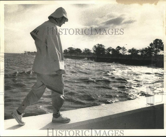 Press Photo Man walks by body of water in cold weather - noc53991