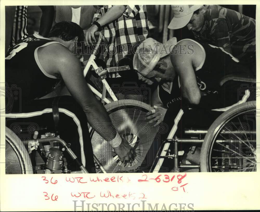 1987 Press Photo Wheelchair basketball players repair spoke on chair.- Historic Images