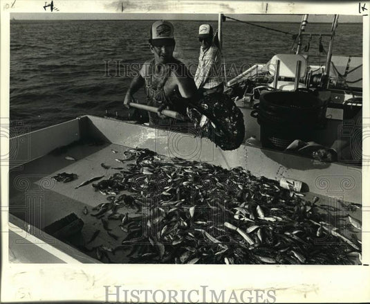 1984 Press Photo Barry Bordeleon sorts shrimp on his skiff as Willie Hof watches- Historic Images