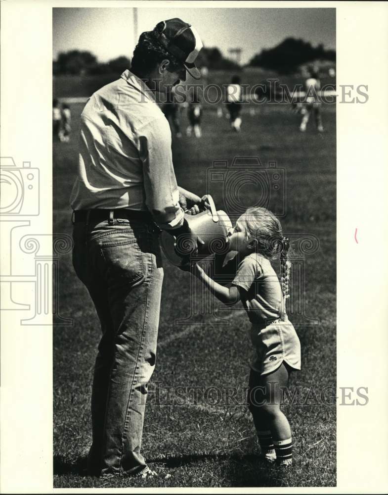 1981 Press Photo Lisa Withey gets drink during a break from her dad John Withey- Historic Images