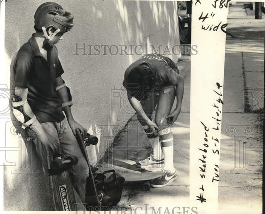 1977 Press Photo Padded and protected skateboarder Michael Martin tends scrape.- Historic Images
