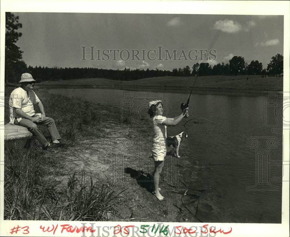 1986 Press Photo Emily Sporl tries luck with catfish at the pond on their farm- Historic Images