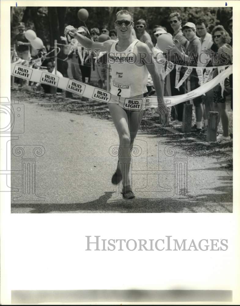 1990 Press Photo Nick Taylor crosses finish line at Crawfishman Triathlon- Historic Images