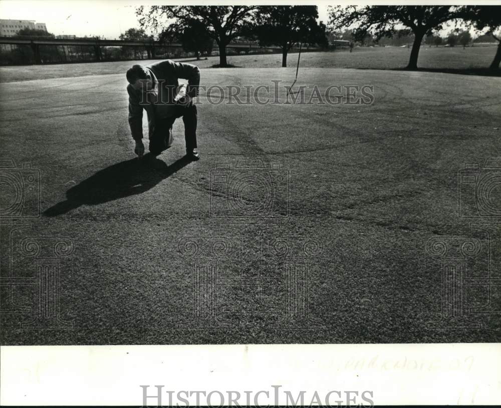 1982 Press Photo Golf player Henry Thomas checks damage to City Park green- Historic Images