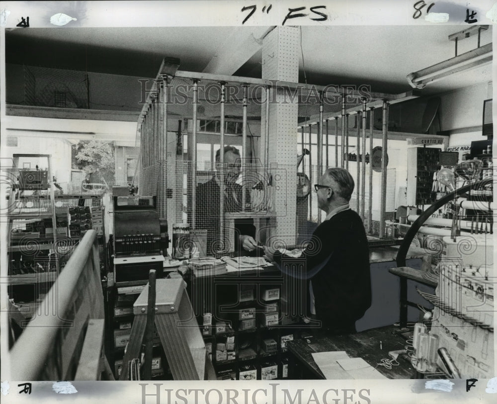 1975 Press Photo Sidney Brewer serves through bars at hardware store in Gentilly
