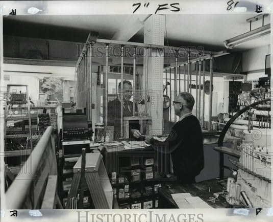 1975 Press Photo Sidney Brewer serves through bars at hardware store in Gentilly