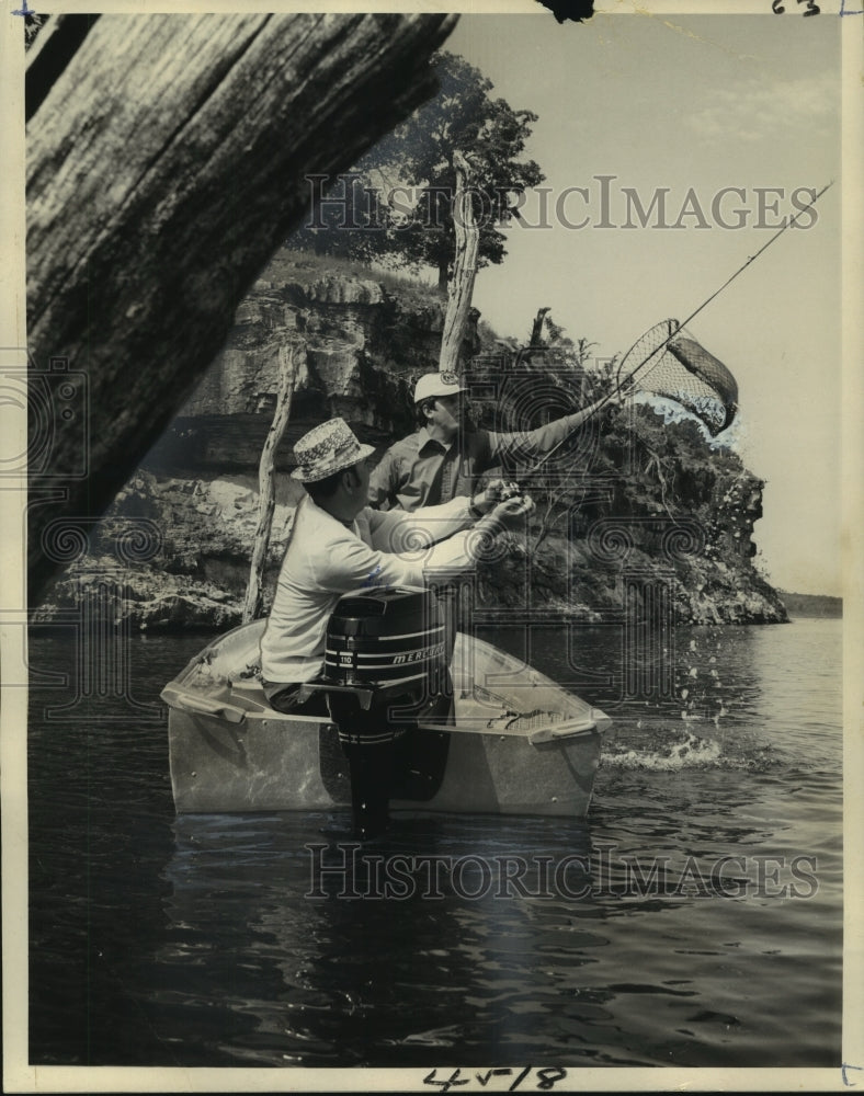 1976 Press Photo Two fishermen netting a fish from their boat - noo17196