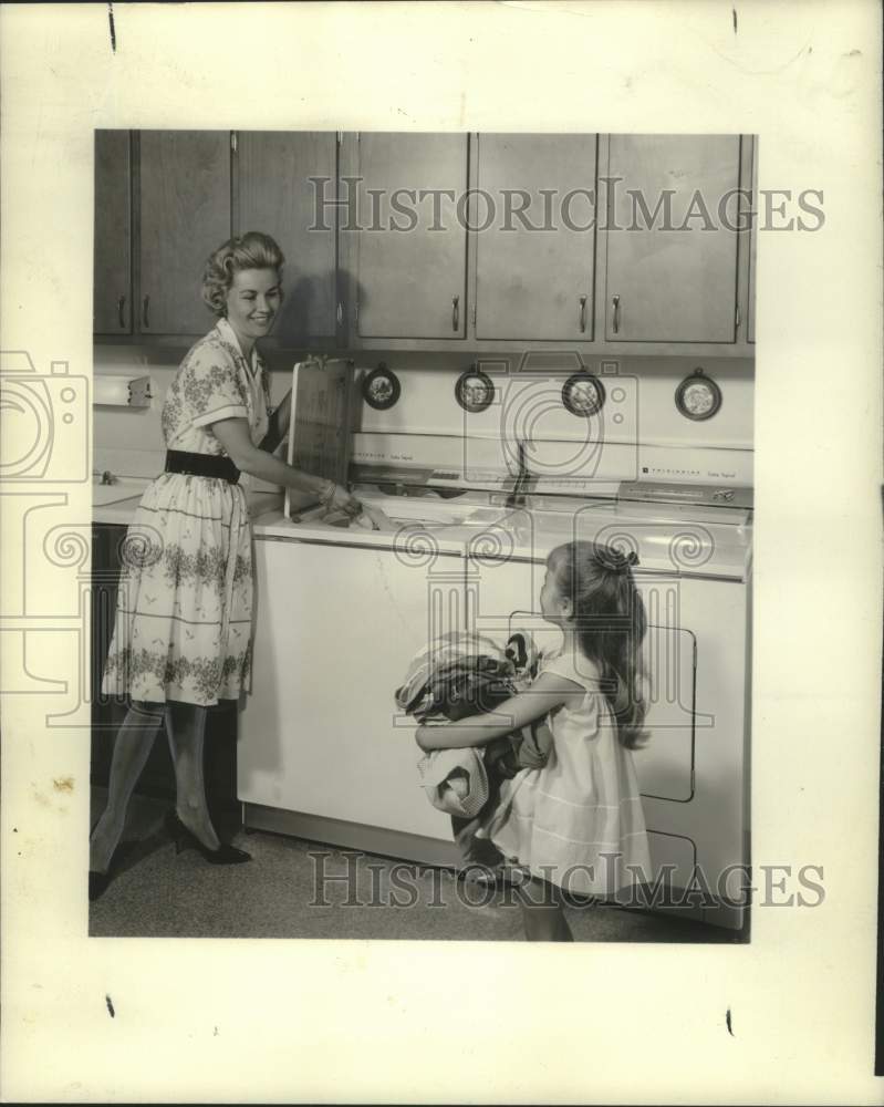 Load image into Gallery viewer, 1962 Press Photo Mother and child loading laundry in Frigidaire washer
