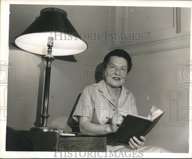 Load image into Gallery viewer, 1959 Press Photo Novelist Gwen Bristow reads by lamp - nop09829
