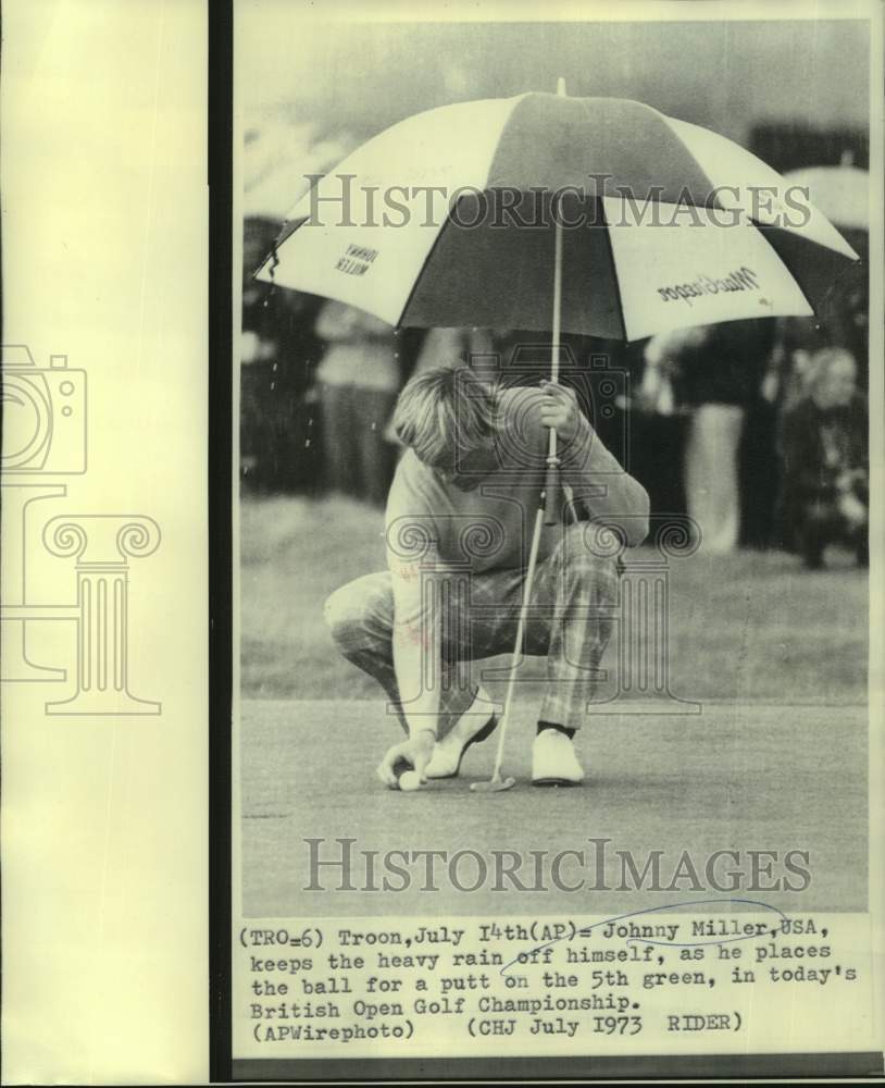 1973 Press Photo Golfer Johnny Miller holds umbrella as he places his ball- Historic Images