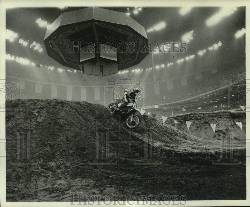 1977 Press Photo Motocross racer goes over hill on dirt track in LA Superdome- Historic Images