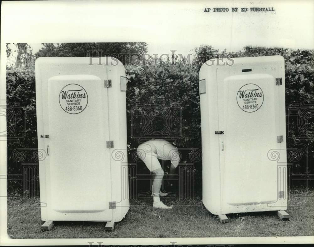 1973 Press Photo Man finds golf ball under bushes between two port-a-potties- Historic Images