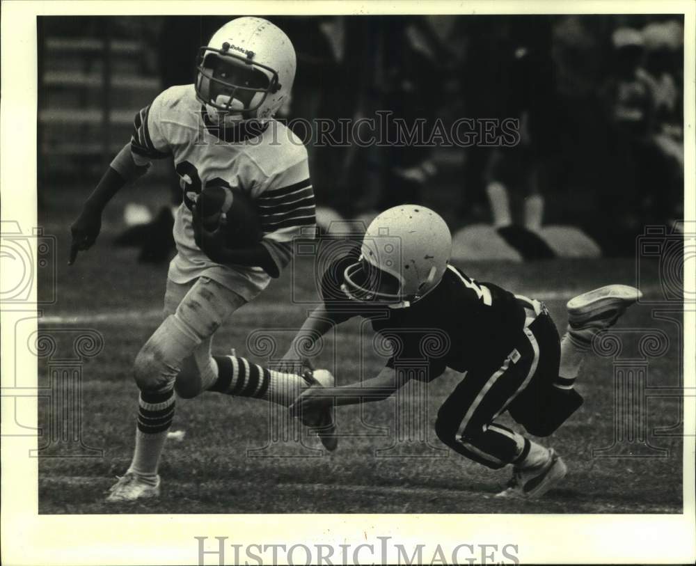 1984 Press Photo Harvey Saint football running back Shombe Boston eludes tackle- Historic Images