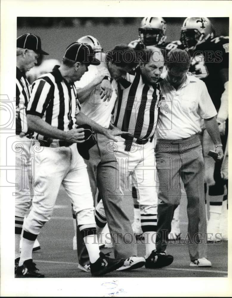 1988 Press Photo Saints Trainers assist Umpire Rex Stuart off Field after injury- Historic Images