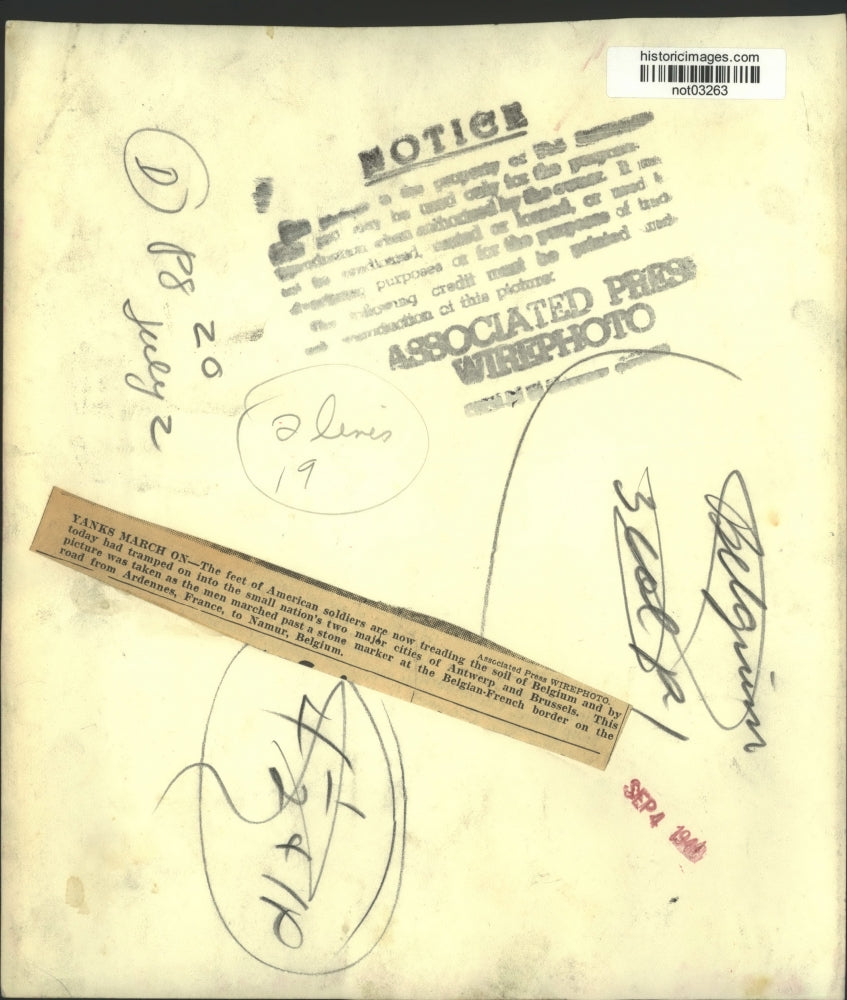 1944 Press Photo U.S. soldiers march by a marker at the Belgian-French border