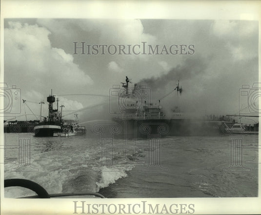 1977 Press Photo Several boats hose down a large ship on fire in the water