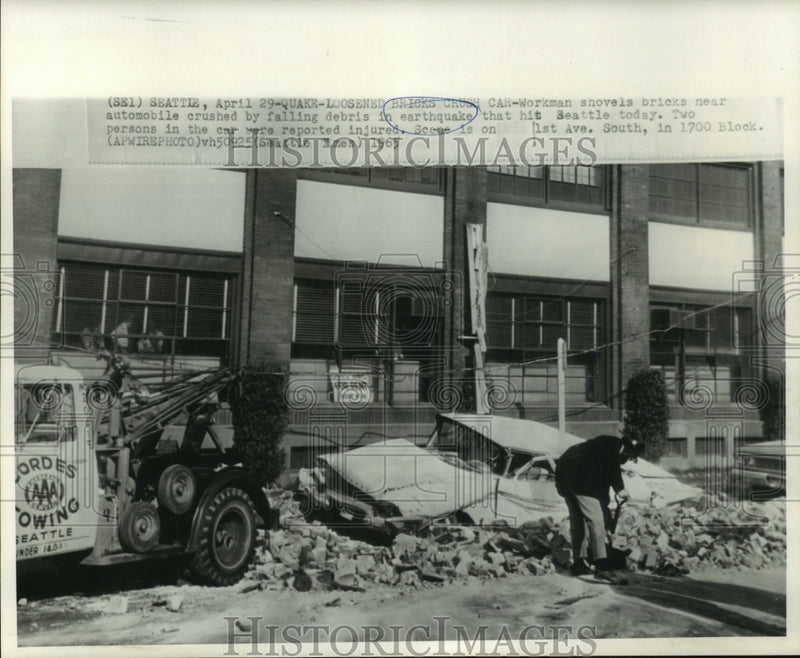 Load image into Gallery viewer, 1965 Press Photo Workman shovels near crushed automobile by earthquake debris
