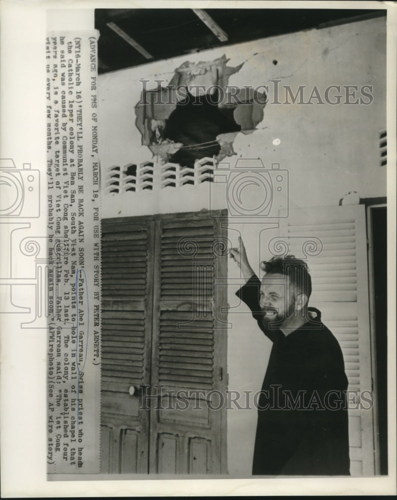 1963 Press Photo Father Abel Garreau points to Viet Cong shelling damage