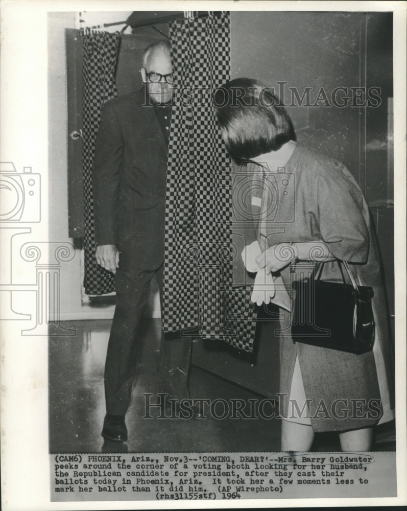 1964 Press Photo Mrs. Barry Goldwater peeks around voting booth for her husband