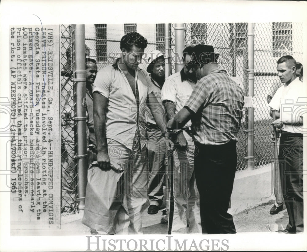 1963 Press Photo Prison guard checks convicts handcuffs during prison transfer.