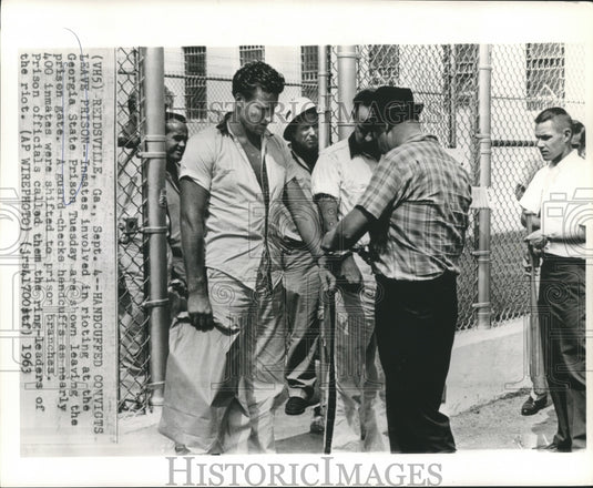 1963 Press Photo Prison guard checks convicts handcuffs during prison transfer.