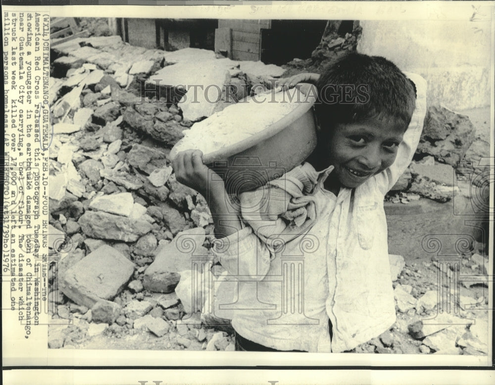 1976 Press Photo Guatemalan boy carries bowl of flour amidst earthquake rubble