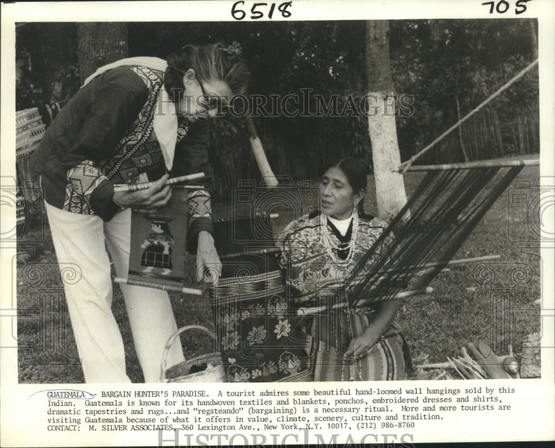 Load image into Gallery viewer, 1980 Press Photo Tourist admires hand-loomed wall hangings in Guatemala
