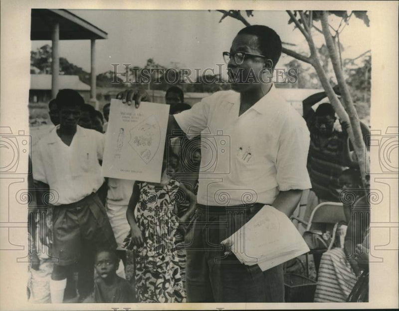 Load image into Gallery viewer, 1962 Press Photo Ghana health worker distributes cooking method handbills
