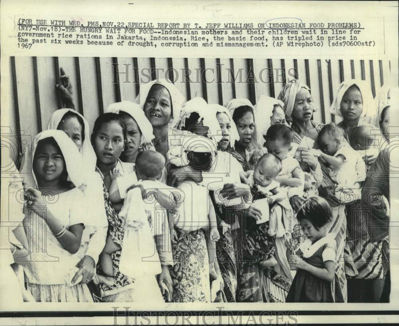 Load image into Gallery viewer, 1967 Press Photo Jakarta, Indonesia mother and children wait for rice rations.
