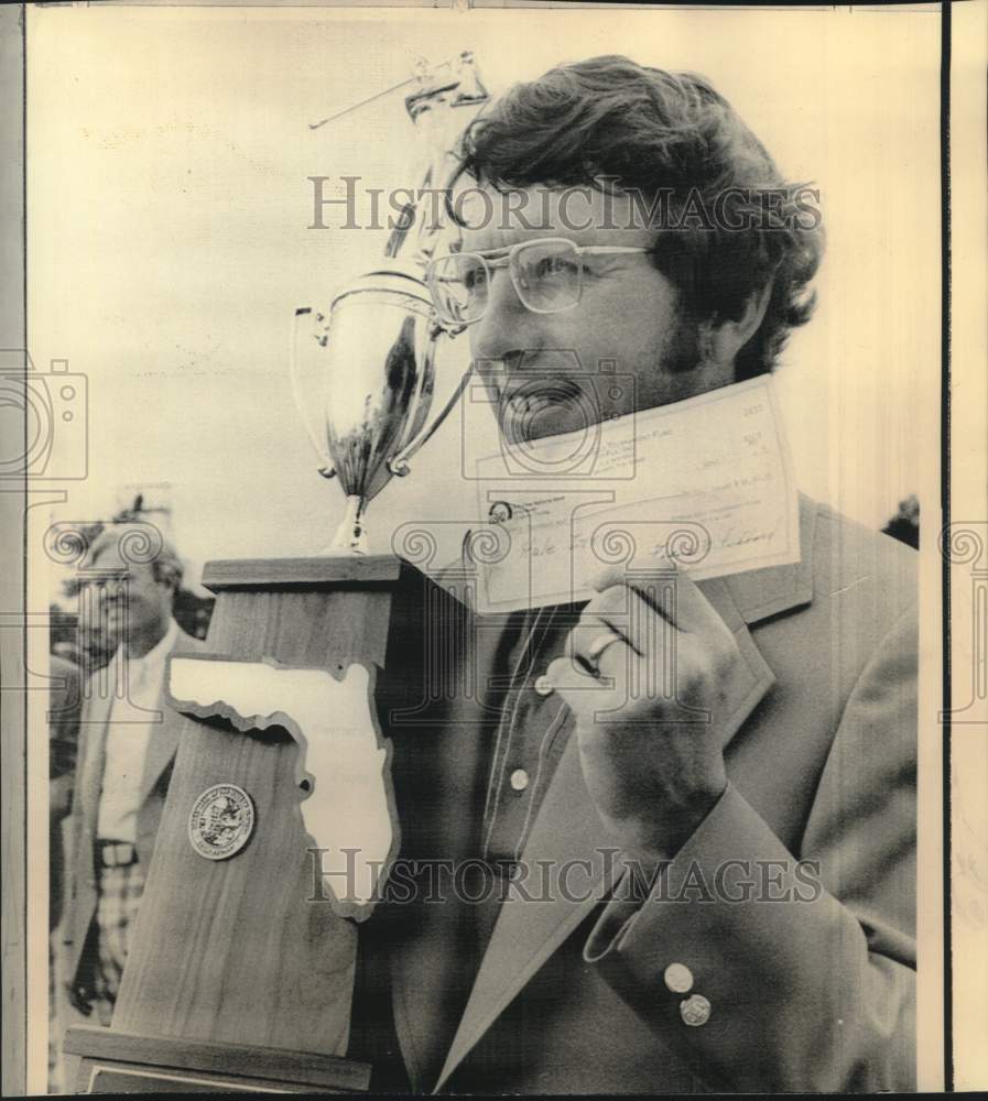 1976 Press Photo Hale Irwin, champion golfer, holds up check and trophy.