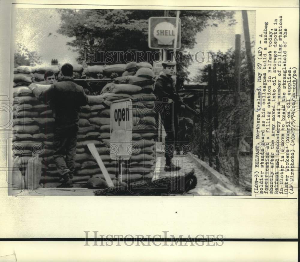 1974 Press Photo Soldier stands guard as others build sandbag fortification