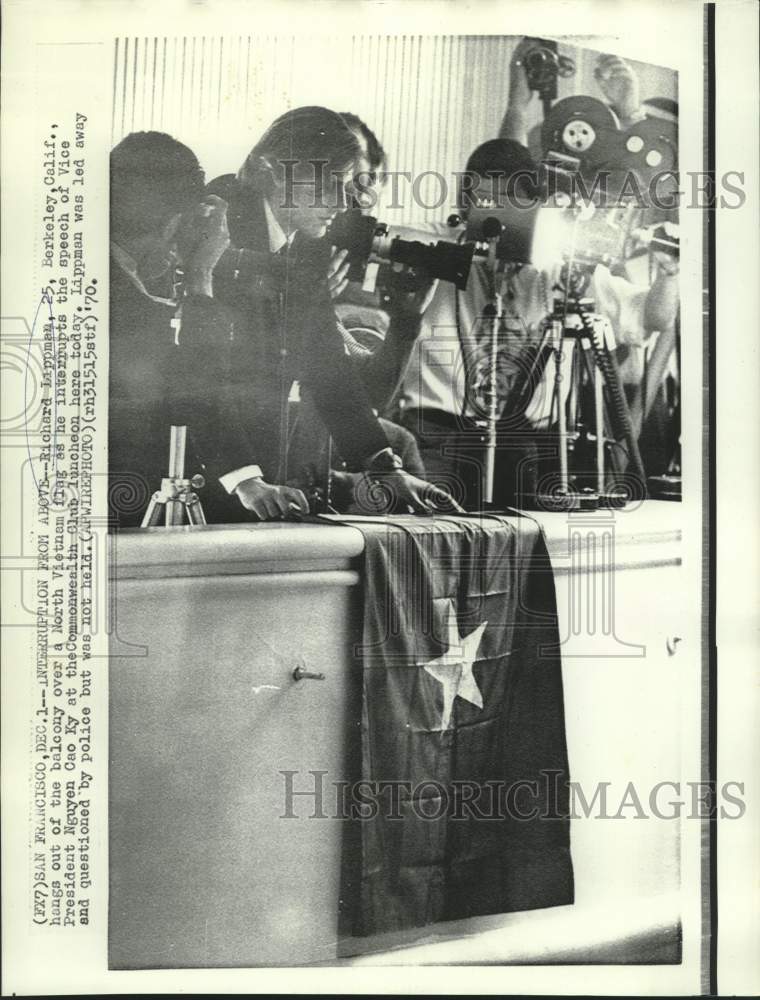 1970 Press Photo Richard Lippmann hangs over balcony with North Vietnam flag.
