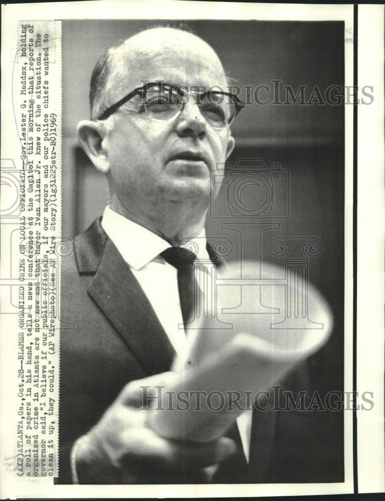 1969 Press Photo Governor Maddox holds roll of newspapers at press conference