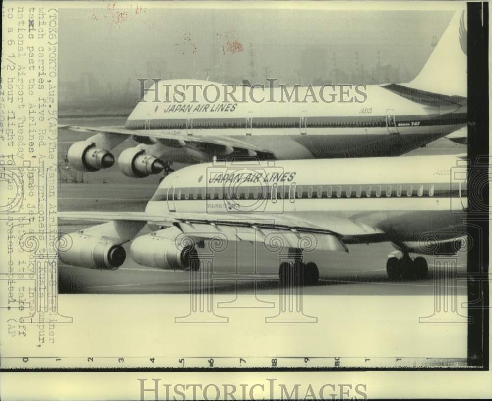 1975 Press Photo Japanese airliner with Red Army prisoners taxis past jumbo jet