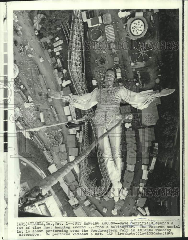 1969 Press Photo Aerialist Dave Merrifield hangs from helicopter at fair event