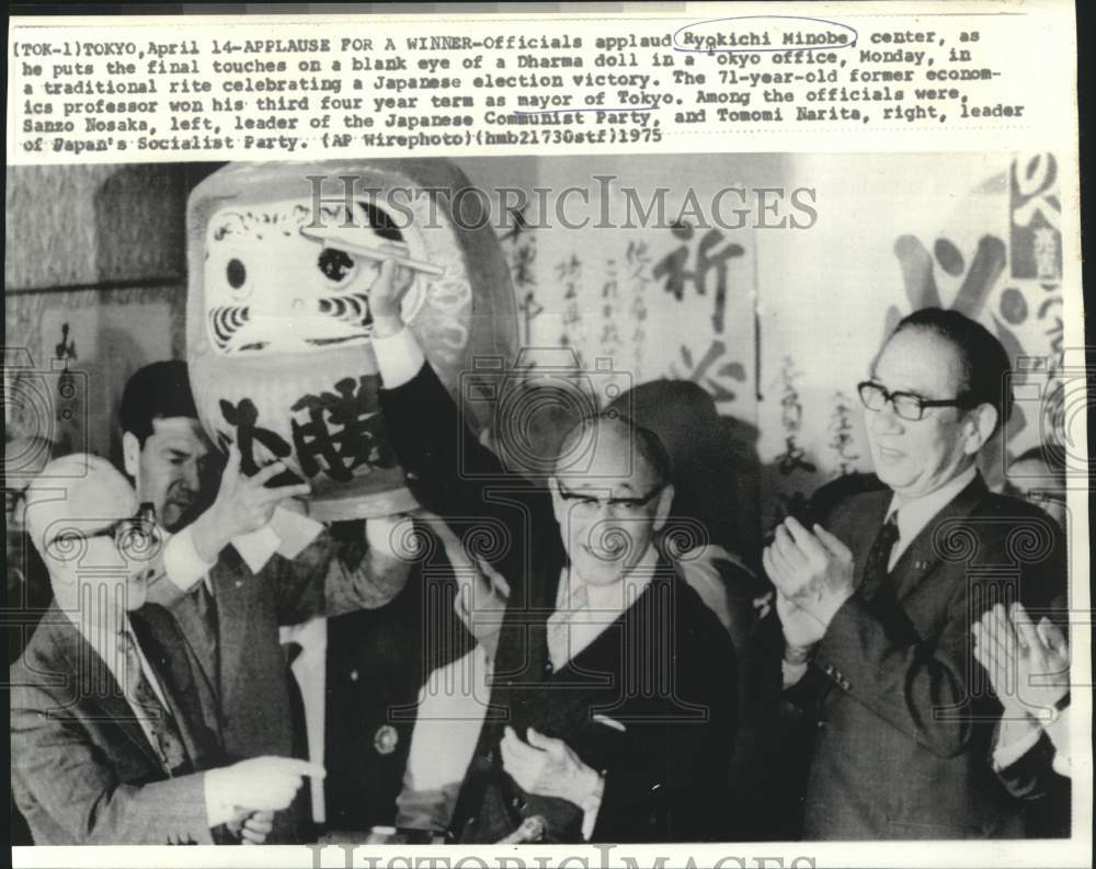 1975 Press Photo Ryokichi Minobe touches blank eye of unfinished Dharma doll.